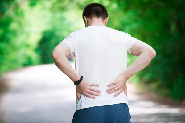 Man with back pain, kidney inflammation, trauma during workout, outdoors concept