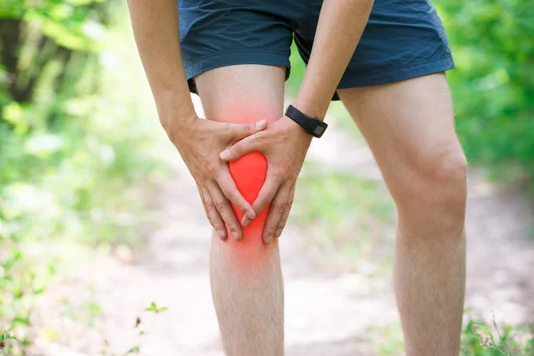 Pain in knee, joint inflammation, massage of male leg, injury while running, trauma during workout, outdoors concept