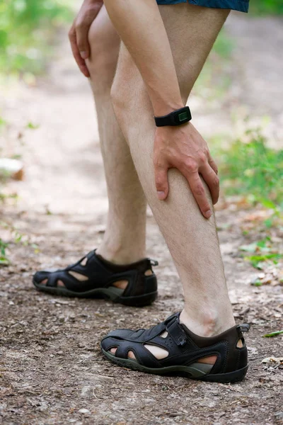 Pain in calf muscle, sprains on the leg, massage of male foot, injury while running, trauma during workout, outdoors concept