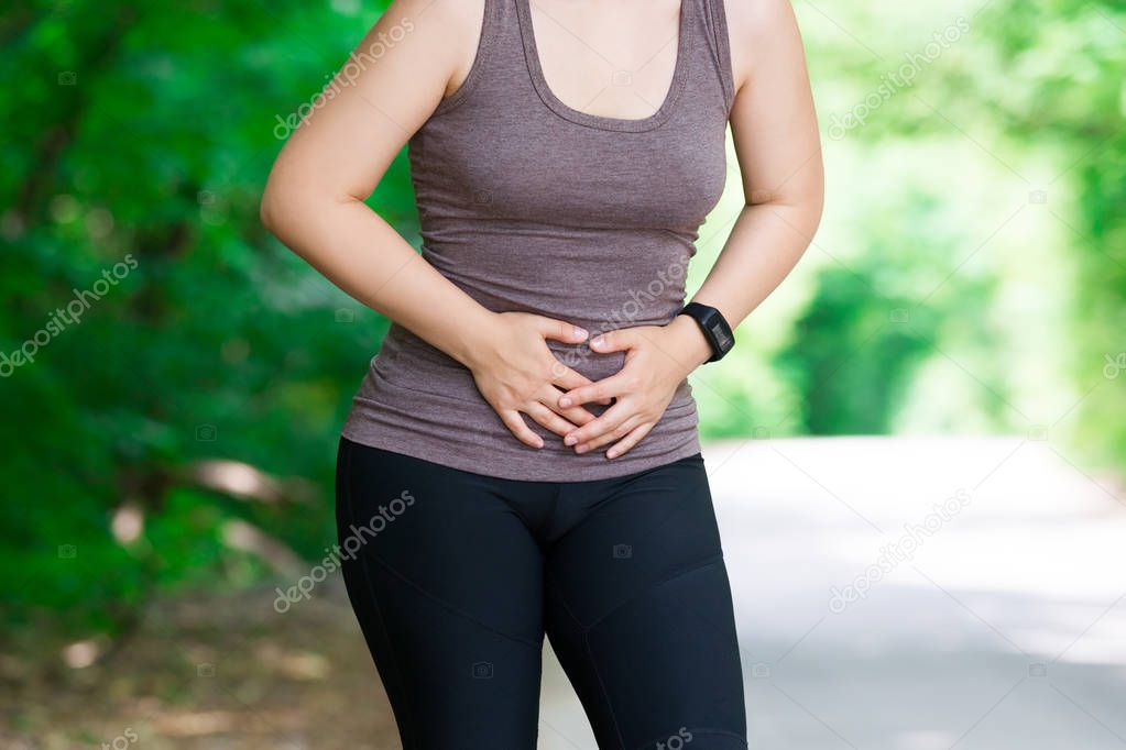 Woman with abdominal pain, injury while running, trauma during workout, outdoors concept
