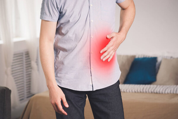 Stomach ache, man with abdominal pain suffering at home, painful area highlighted in red