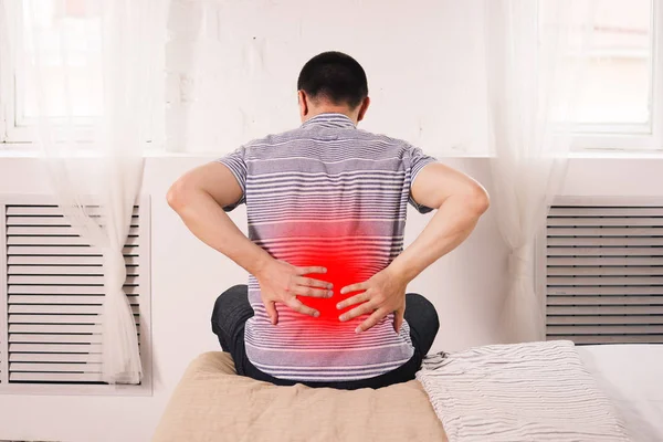 Back pain, kidney inflammation, man suffering from backache at home, painful area highlighted in red
