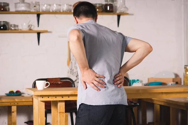 Back pain, kidney inflammation, man suffering from backache at home