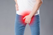 Schmerzen in der Prostata, Mann, der an Prostatitis oder Geschlechtskrankheit leidet, Studioaufnahme auf grauem Hintergrund, Schmerzbereich rot hervorgehoben