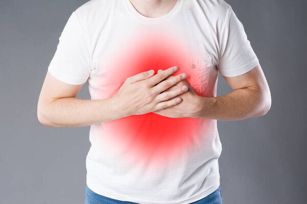 Heart attack, man with chest pain on gray background, painful area highlighted in red