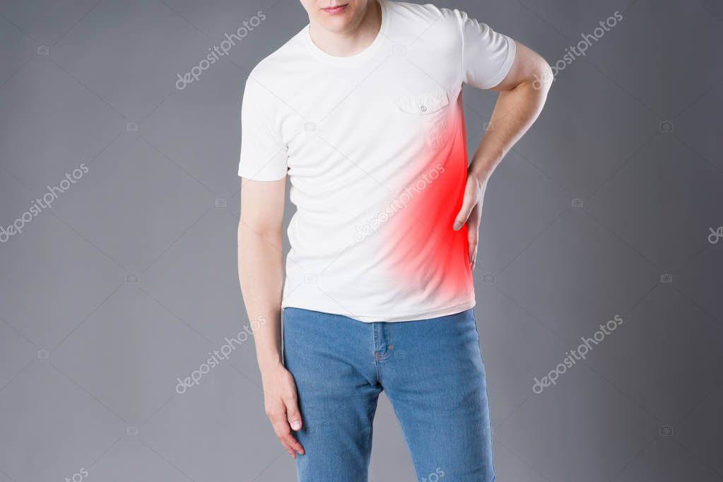 Stomach ache, man suffering with abdominal pain on gray background, painful area highlighted in red
