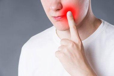 Man suffering from herpes virus on the lip, studio shot on gray background, painful area highlighted in red clipart