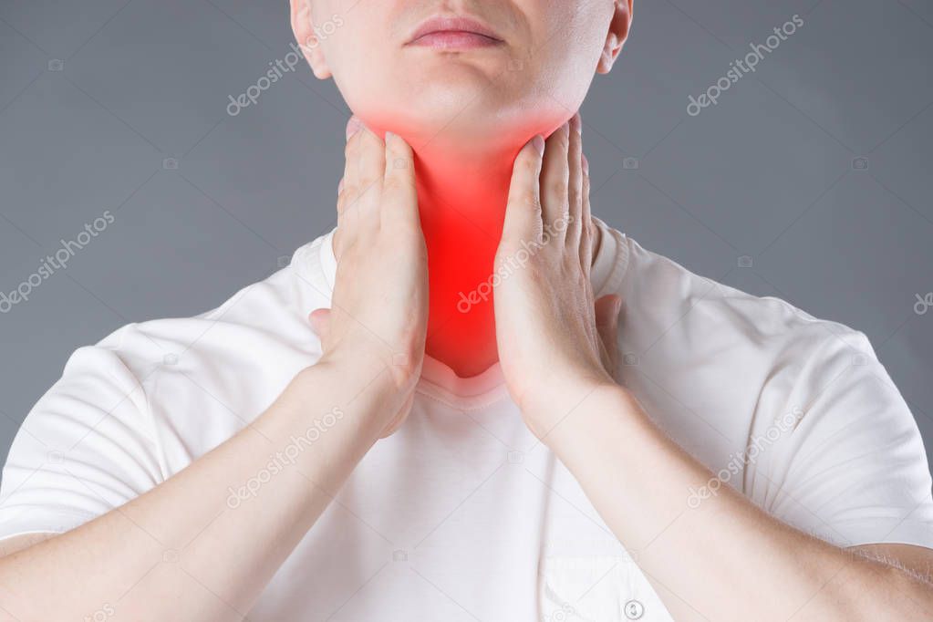 Sore throat, men with pain in neck, studio shot on gray background, painful area highlighted in red
