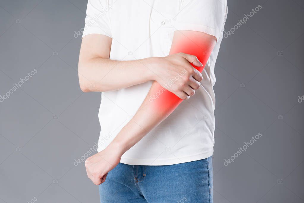 Man suffering from pain in elbow, joint inflammation, painful area highlighted in red