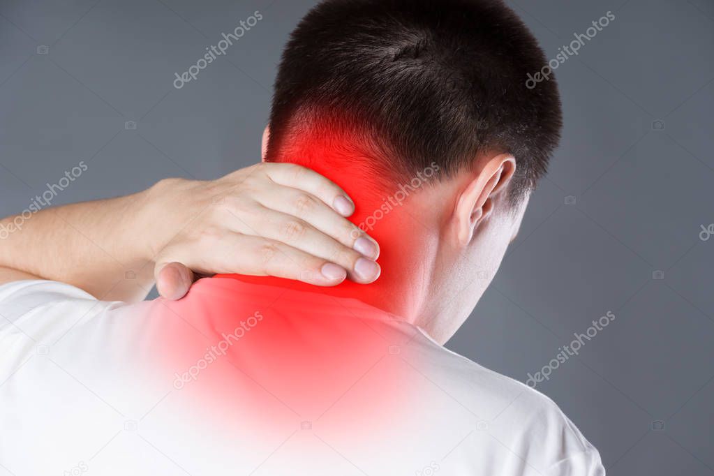 Neck pain, man suffering from backache on gray background, painful area highlighted in red