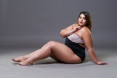 Plus Size Model im sexy Badeanzug, dicke Frau auf grauem Studiohintergrund, übergewichtiger weiblicher Körper, Ganzkörperporträt