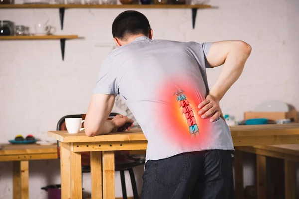 Pain in the spine, a man with backache at home, injury in the lower back, photo with highlighted skeleton — Stock Image Pain Spine Man Backache Home Injury Lower Back Photo Highlighted Stock Image