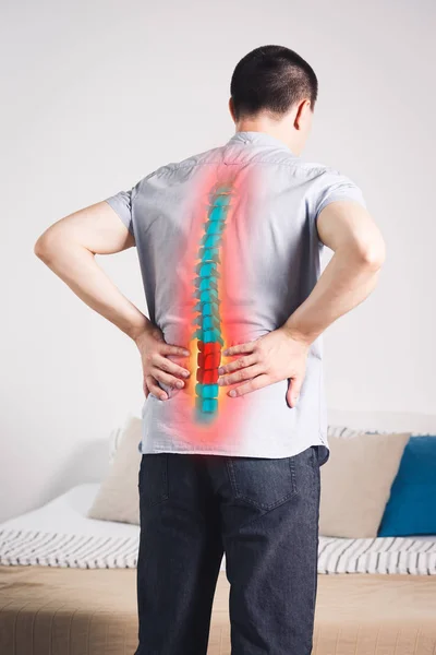 Pain in the spine, a man with backache at home, injury in the lower back, photo with highlighted skeleton — Stock Image Pain Spine Man Backache Home Injury Lower Back Photo Highlighted Royalty Free Stock Photos