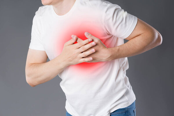 Heart attack, man with chest pain on gray background with red dot