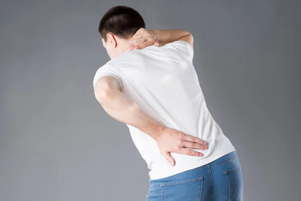 Back pain, man with backache on gray background, studio shot