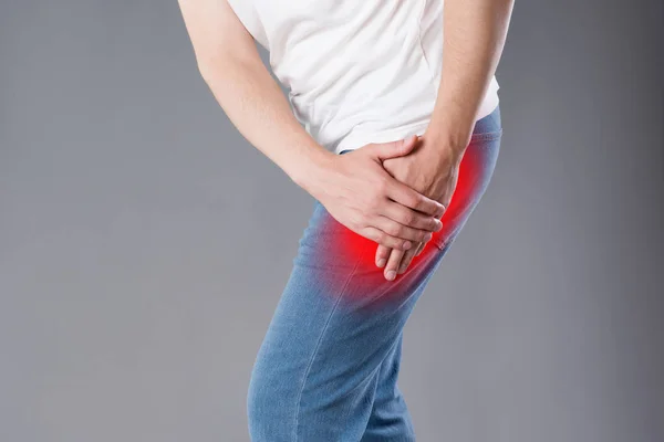 膝盖疼痛的男子 工作室拍摄灰色背景 痛苦的区域突出显示红色 — 图库照片