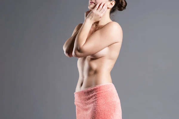 Sexy topless woman after shower in towel on gray background, wellness and spa concept, studio shot