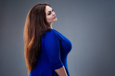 Esmer artı boyutu model mavi elbiseli, gri arka plan, saç modeli ve saç bakım kavramı üzerinde uzun düz saçlı şişman kadın moda