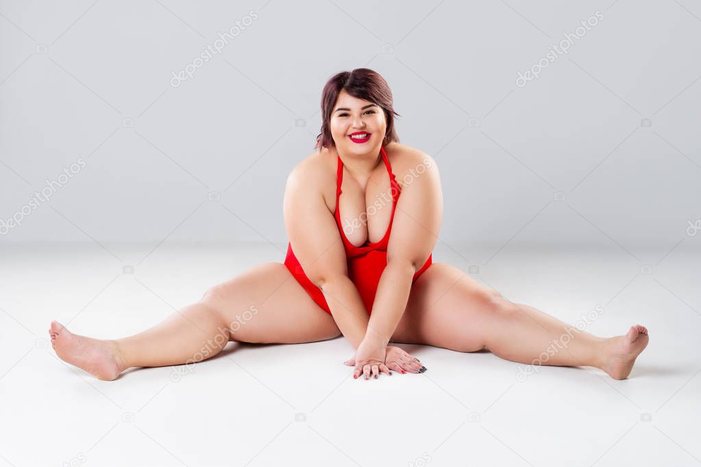 Plus size fashion model in red lingerie, fat woman in underwear on gray studio background, overweight female body, full length portrait