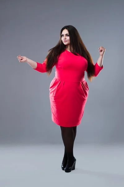 Брюнетка плюс размер модели в красном платье, толстая женщина с длинными волосами на сером фоне, тело положительное понятие — стоковое фото