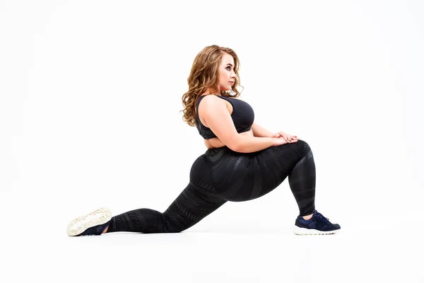 Modelo de tamaño grande en ropa deportiva, mujer gorda haciendo ejercicio sobre fondo blanco, concepto positivo para el cuerpo —  Fotos de Stock