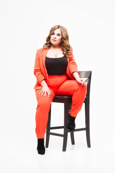Modelo de tamaño grande con pecho grande y escote profundo, mujer gorda sobre fondo blanco en traje pantalón naranja, concepto positivo para el cuerpo —  Fotos de Stock