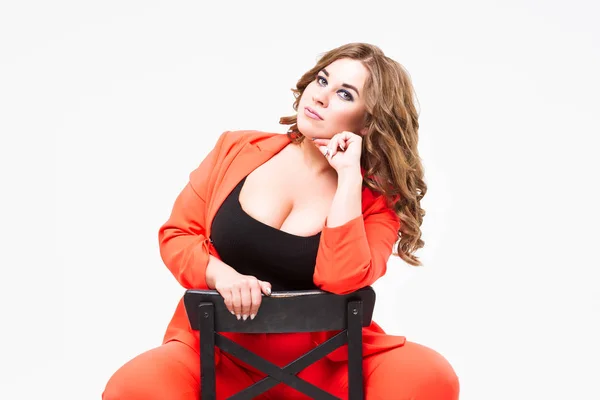 Плюс модель большого размера с большой грудью и глубокой декольте, толстая женщина на белом фоне в оранжевом брючном костюме, позитивный образ тела — стоковое фото