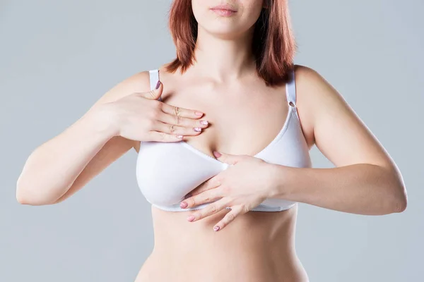 Borst test, vrouw onderzoekt haar borsten voor kanker, grote natuurlijke tieten op grijze achtergrond — Stockfoto