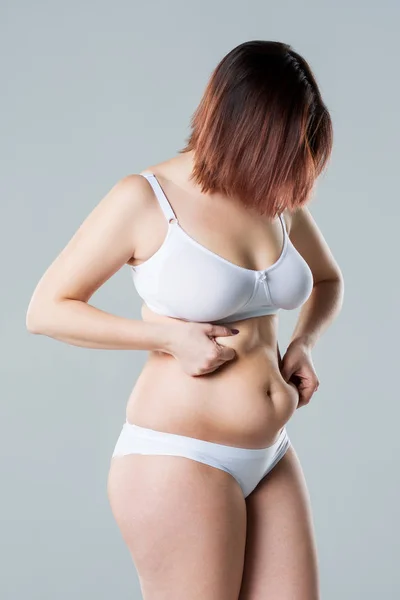 Frau mit fettem schlaffen Bauch, übergewichtiger weiblicher Körper auf grauem Hintergrund — Stockfoto