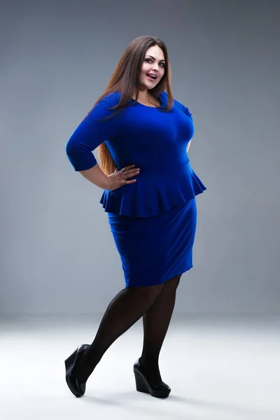 Glücklich plus size fashion model in blue dress, fat woman on grey studio background, body positive concept — Stockfoto