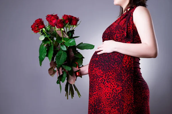 Femme enceinte avec bouquet de roses rouges sur fond gris — Photo