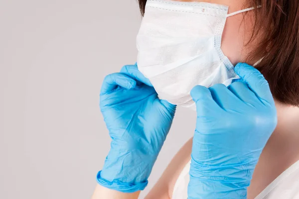 Woman with face mask and nitrile gloves on grey background, outbreak of coronavirus disease 2019 or covid-19