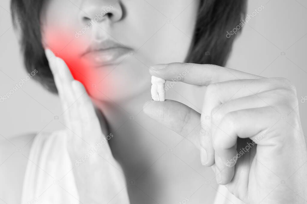 Wisdom tooth extraction, woman suffering from a toothache on gray background, painful area highlighted in red