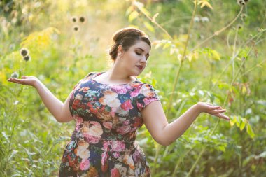 Ayrıca açık havada çiçek desenli bir manken, büyük göğüsleri olan güzel şişman bir kadın, vücut pozitifliği.