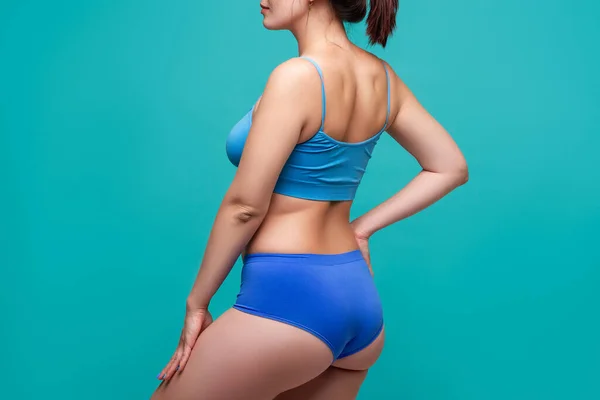 ターコイズの背景に青い下着を着た女性 ボディケアの概念 — ストック写真