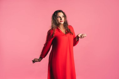 Artı, pembe arka planda kırmızı elbiseyle beden pozitifliği.