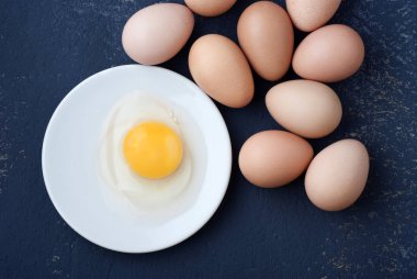 Mavi arka plan yakın çekim üzerinde beyaz bir tabak içinde çiğ yumurta tavuk