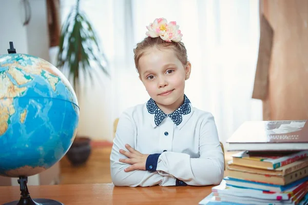 Een schoolmeisje zit achter een bureau — Stockfoto
