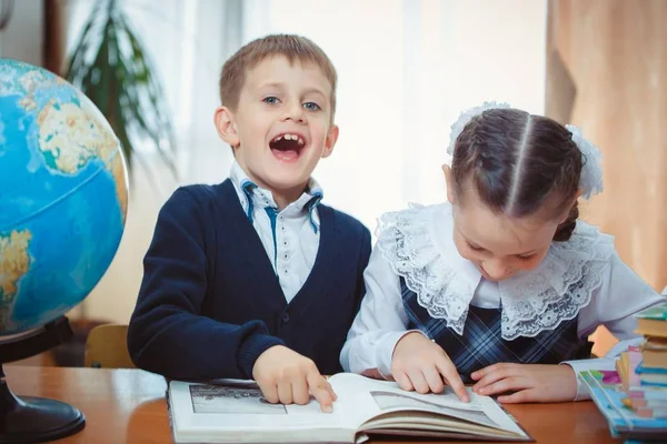 Skolpojke och skolflicka med en jordglob — Stockfoto