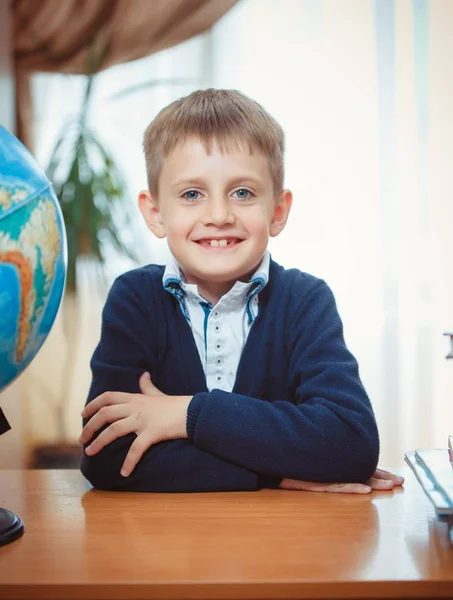 Een schooljongen zit achter een bureau — Stockfoto