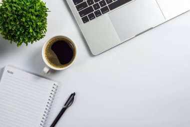 Kahve fincanı, boş defter, siyah kalem, dizüstü bilgisayar ve bitki pot, üstten görünüm tasarımı ile ofis masası