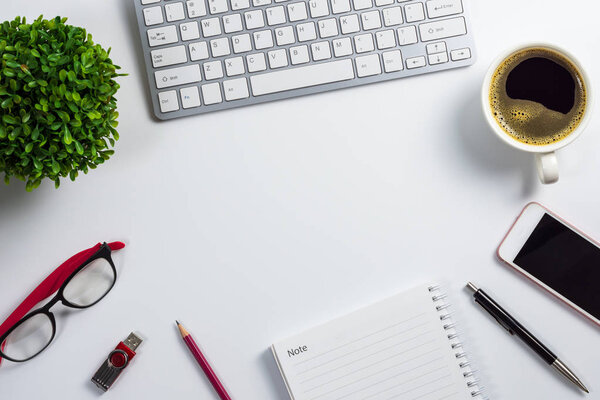 Top view, flat design office desk with computer keyboard, coffee cup, smart phone, pen, notebook, pencil, flash drive, glasses and plant pot