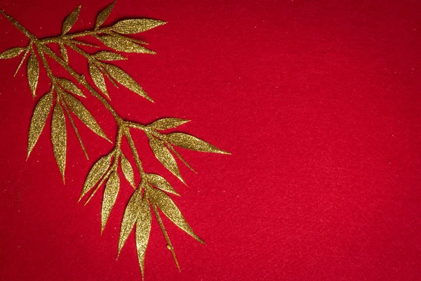 Golden tree leaves on red flannel background, top view design