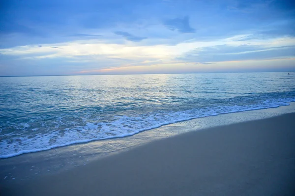 Krajina písčité pláže s jemnou vlnou a východem slunce s mrakem — Stock fotografie