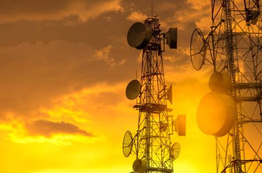 Altın gökyüzünde kablosuz antenleri olan telekomünikasyon kuleleri