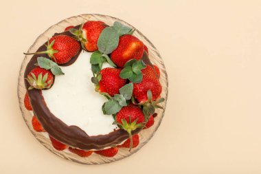 Ev yapımı çikolatalı kek taze çilek cam levha ve bej renk arka plan ile dekore edilmiştir. Kopya alanı ile üstten görünüm