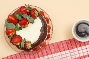 Ev yapımı çikolatalı kek taze çilek ve cam tabakta nane yaprakları ve kahve bej renk arka plan üzerinde mutfak peçete ile süslenmiş. Üstten görünüm