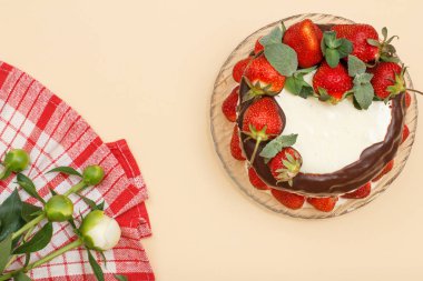 Ev yapımı çikolatalı kek taze çilek ve bej renk arka plan üzerinde peonies buket cam plaka ve mutfak peçete nane yaprakları ile süslenmiş. Üstten görünüm