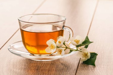 Cam bardak yeşil çay ahşap arka plan üzerinde beyaz yasemin çiçekleri ile