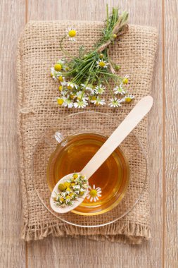 Cam bardak yeşil çay ahşap arka plan üzerinde beyaz papatya çiçeği ile. Üstten görünüm